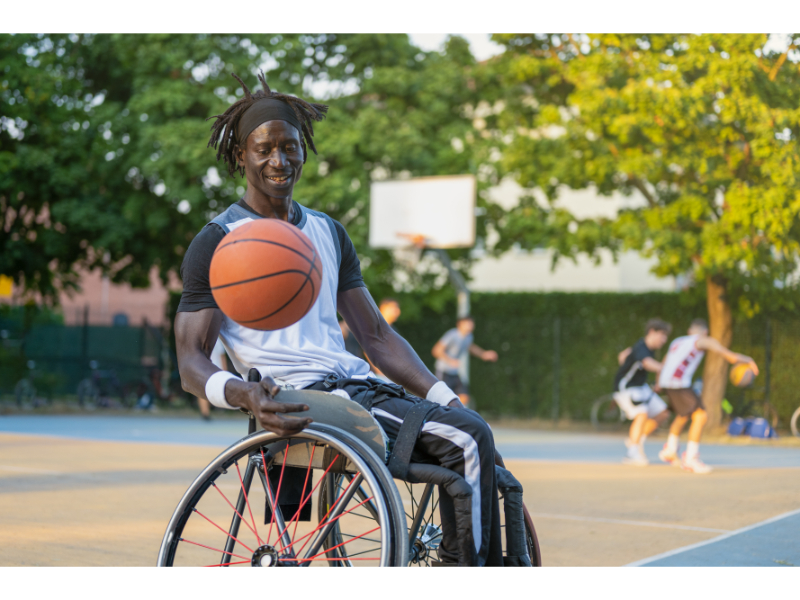 Adult plays basketball while in a wheelchair
