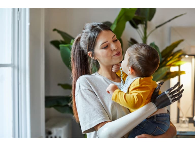 Adult with arm prosthetic holds a baby