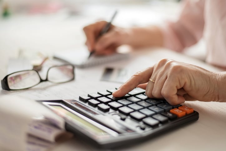 Older adult calculates finances at a table.