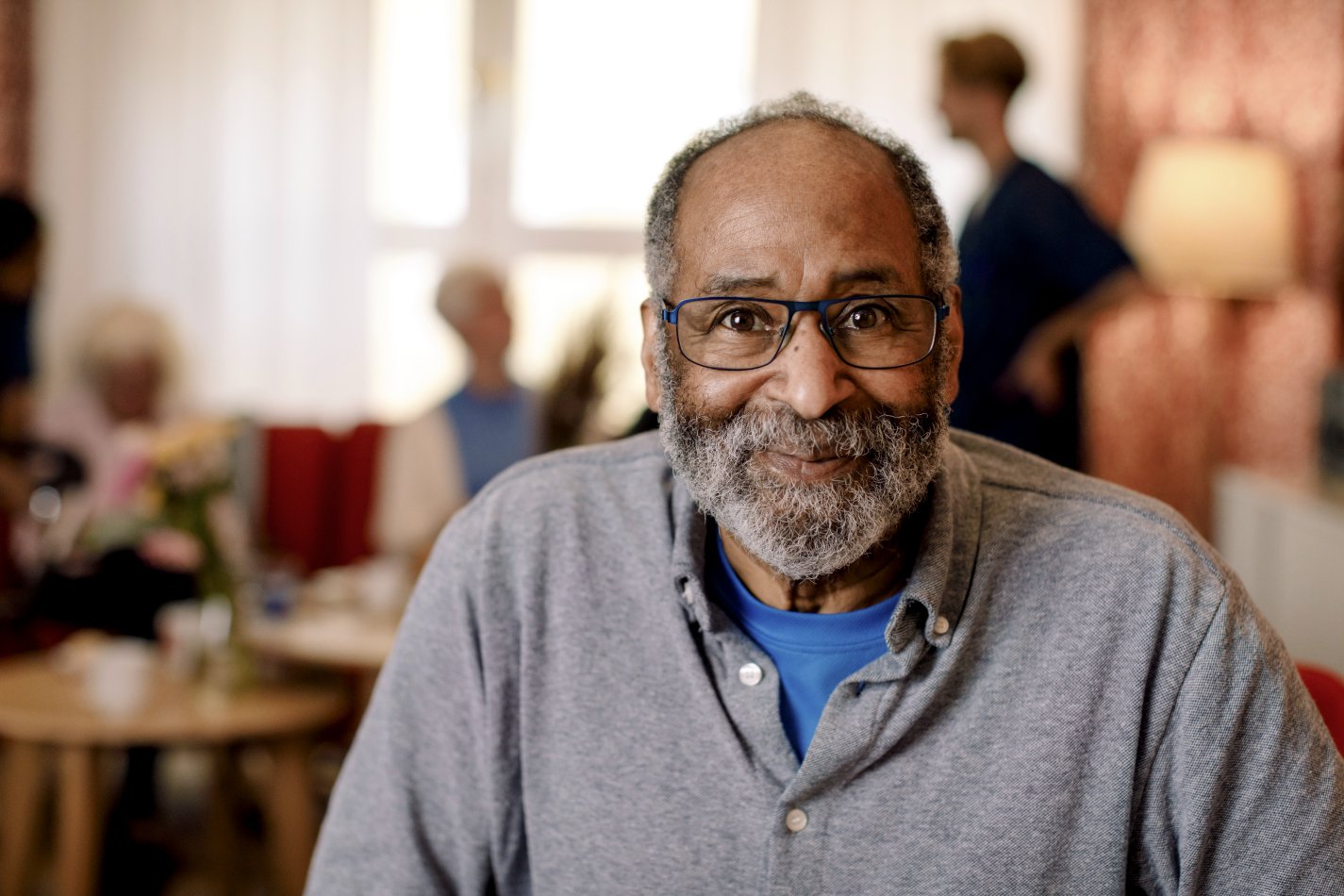 Older adult in a nursing home smiles at the camera.
